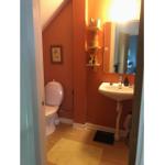 Badezimmer mit Toilette, Waschbecken und Spiegel an orangefarbenen Wänden.