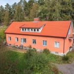 Ein orangefarbenes Haus mit rotem Dach steht inmitten von Bäumen.