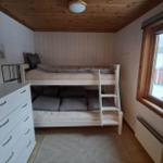 Zimmer mit Doppelstockbett, Schrank und Fenster mit Blick auf Haus und Schnee.