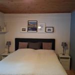 Schlafzimmer mit Doppelbett, Nachttischen und Wanddekoration.