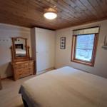 Schlafzimmer mit Holzdecke, Bett, Kleiderschrank und Fenster mit Blick.
