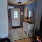 Eingangsbereich mit Holzdecke, Schrank und Kaminofen mit brennendem Feuer.