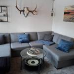Grauer Ecksofa mit blauen Kissen und Glas-Tisch im Wohnzimmer.