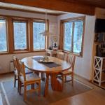 Esszimmer mit Holztisch, Stühlen und Fenstern zum Wald. Fernseher und Schrank sind sichtbar.