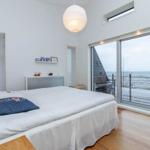 Schlafzimmer mit Blick aufs Meer und Holzboden.