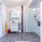 Badezimmer mit Dusche, Waschbecken und Toilette. Fliesen an den Wänden und Boden.