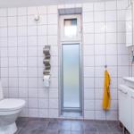 Badezimmer mit Toilette, Waschbecken und Dusche mit Glaswand.
