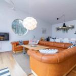 Wohnzimmer mit braunem Sofa, runden Fenster und Holzboden.