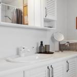 Waschbecken mit Spiegel, Waschmaschine und Badezimmer im Hintergrund.