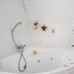 Eine weiße Whirlpool-Badewanne mit Duschkopf und dekorativen Wandhaltern.
