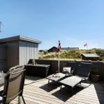 Terrasse mit Liegestühlen und Tisch. Blick auf Grasland und Flagge.