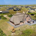 Haus mit Strohdach, Terrasse und Spielplatz auf grünem Grundstück