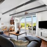 Wohnzimmer mit Sofa, TV und großem Fenster zum Balkon.
