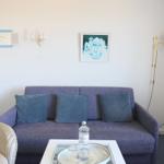 Ein Wohnzimmer mit einem blauen Sofa, einem runden Tisch und einer Wandlampe.