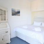 Schlafzimmer mit weißem Bett, Schrank und Wandbild