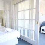 Schlafzimmer mit Bett und Kleiderschrank. Durchgehende Glaswand trennt Raum vom Wohnbereich.