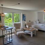 Ein Raum mit Schlafplatz, Sitzgelegenheiten und Tisch. Durchgänge führen zu Balkon und Fenster.