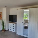 Schlafzimmer mit Kleiderschrank, Fernseher und Pflanze.