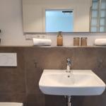 Badezimmer mit Waschbecken, Spiegel und Handtüchern