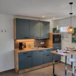 Küche mit Holz Arbeitsplatte, grauen Schränken und Essbereich mit Tisch und Stühlen.