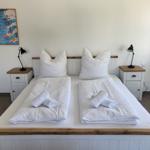 Zimmer mit Doppelbett, zwei Nachttischen und Wandbild.