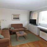 Wohnzimmer mit zwei braunen Sofas, Holzfußboden und großem Fenster.
