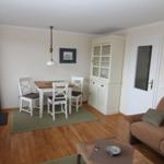 Wohn- und Essbereich mit Sofa, Tisch, Stühlen und Sideboard.