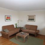 Wohnzimmer mit zwei braunen Sofas, Holztisch, Fernseher und Wandbildern.