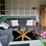 Wohnzimmer mit Sofa, Sessel, Glas-Tisch und Holzsauna