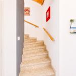 Treppenhaus mit Holzgeländer und Terrazzo-Stufen. Wandbilder zeigen Strand und Blumen.