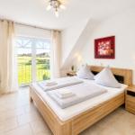 Schlafzimmer mit Doppelbett, Fenster zum Garten und Wandbild.