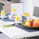 Tisch mit Frühstück, Obstschale und Gläsern mit Saft.
