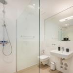 Dusche mit Glaswand, Waschbecken und Toilette in weißer Ausstattung.