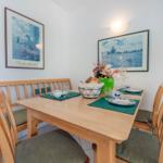 Esszimmer mit Holztisch, Stühlen und Wandbildern.