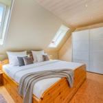 Schlafzimmer mit Doppelbett, Dachschrägen, Fenster und Kleiderschrank.