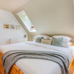Schlafzimmer mit Holzbett, Dachschrägen und Fenstern.