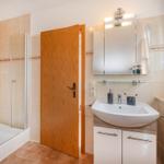 Badezimmer mit Dusche, Waschbecken und Spiegel