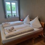 Zimmer mit Doppelbett, Fenster und Holzboden.