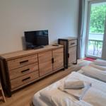 Zimmer mit zwei Betten, Fernseher und Balkonansicht.