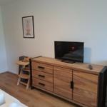 Schlafzimmer mit Holzschrank, Fernseher und Bild an der Wand.