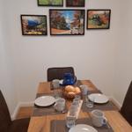 Esszimmer mit Holztisch, Stühlen und Wandbildern