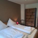 Zimmer mit Doppelbett, Holzregal und Nachttisch mit Lampe.
