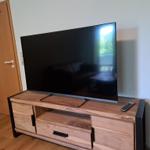 Flachbildfernseher auf Holz-TV-Schrank mit Fernbedienung