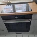 Küchenzeile mit integriertem Herd und Backofen unter Holzoberfläche.