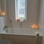 Bad mit Badewanne, Fenster, Kerzen und Handtuchrollen.