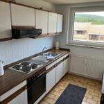 Küche mit Kochfeld, Spüle und Fensterblick auf Dächer und Hügel