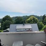 Terrasse mit Sitzgelegenheiten und Blick auf ein Haus und Wald.