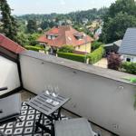 Terrasse mit Tisch, zwei Stühlen und Blick auf Wohnhäuser und Grünflächen.