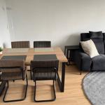 Essbereich mit Tisch und vier Stühlen neben einem dunklen Sofa.