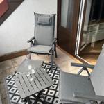 Terrasse mit zwei grauen Sesseln, Tisch und Teppich. Durchgang ins Haus.